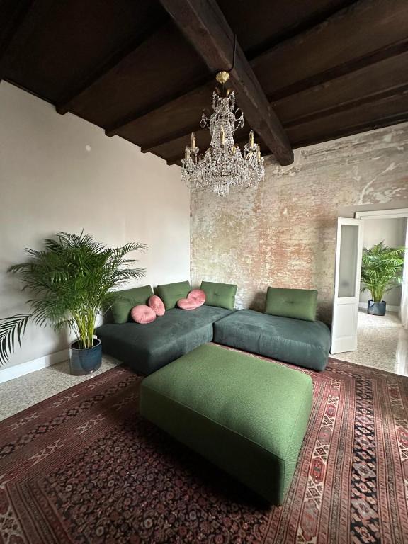a living room with a green couch and a chandelier at Room Manzoni 37 in Cremona