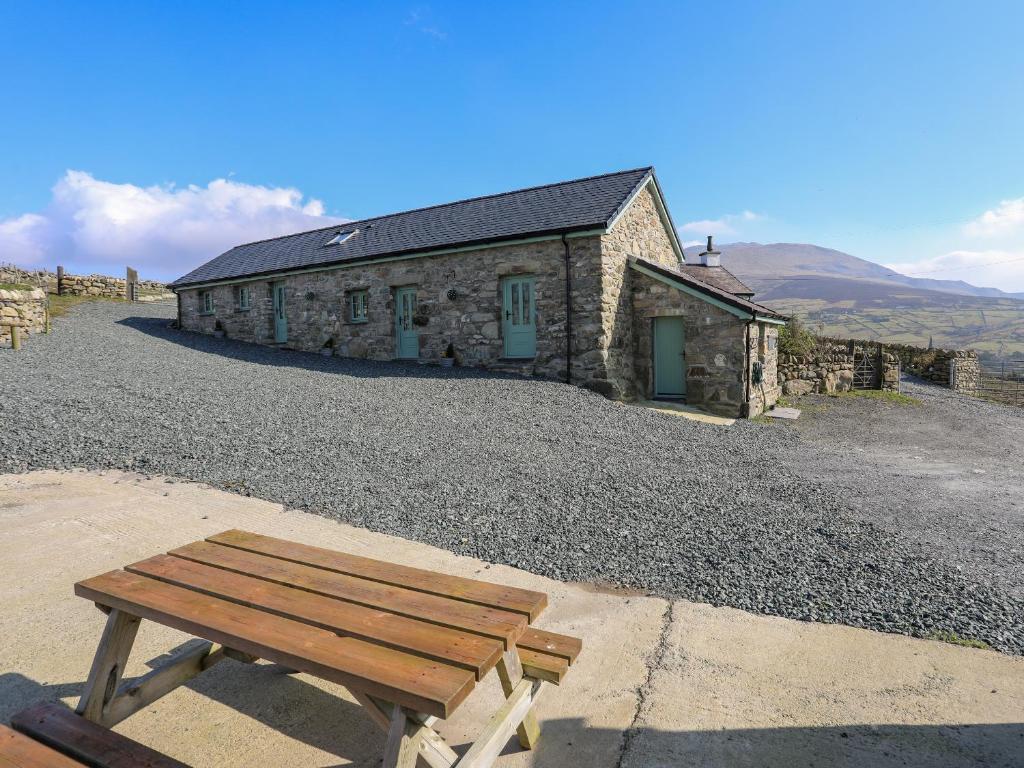 a wooden bench sitting in front of a stone building at Ty Den in Caernarfon