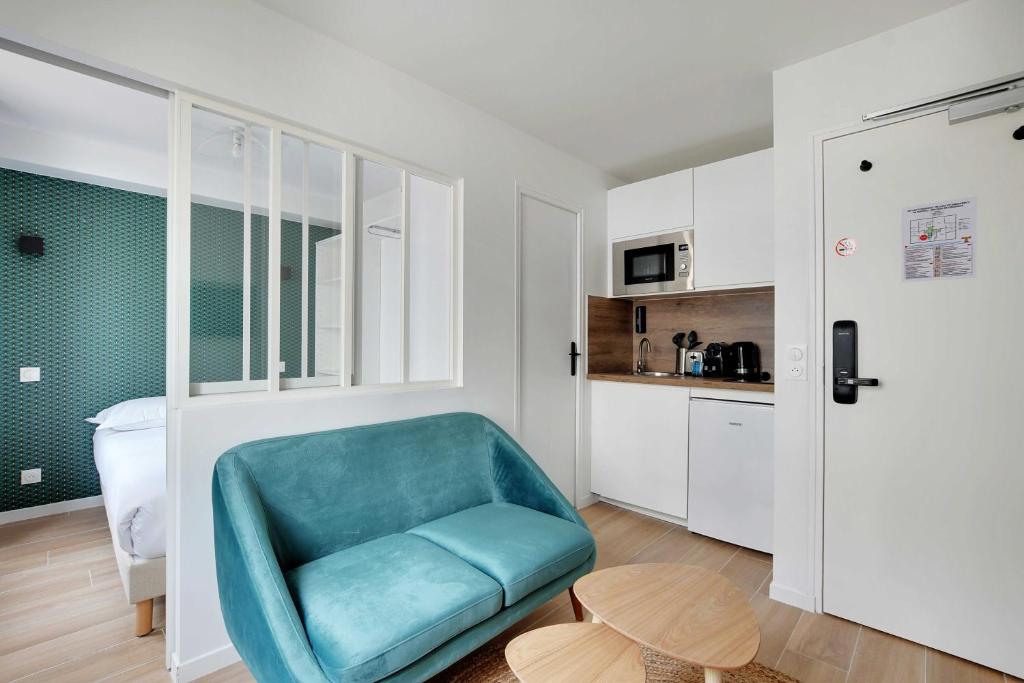 a living room with a blue chair and a kitchen at Small and modern apartment 11rd Paris in Paris