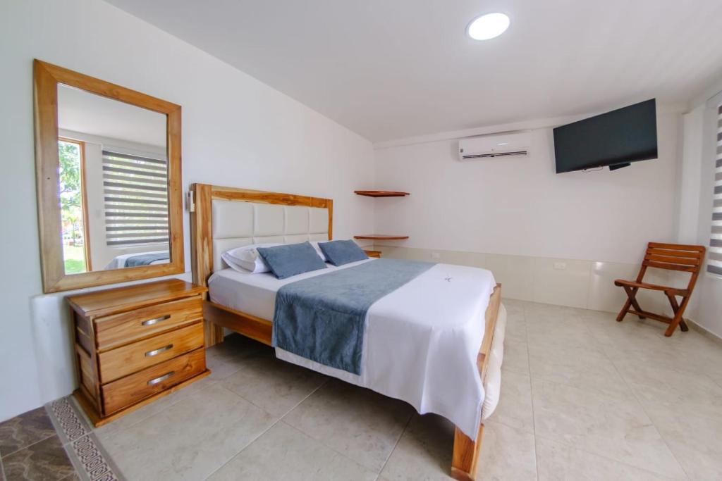 a bedroom with a bed and a dresser and a mirror at HOTEL LLANO CAMPESTRE in La Concepción