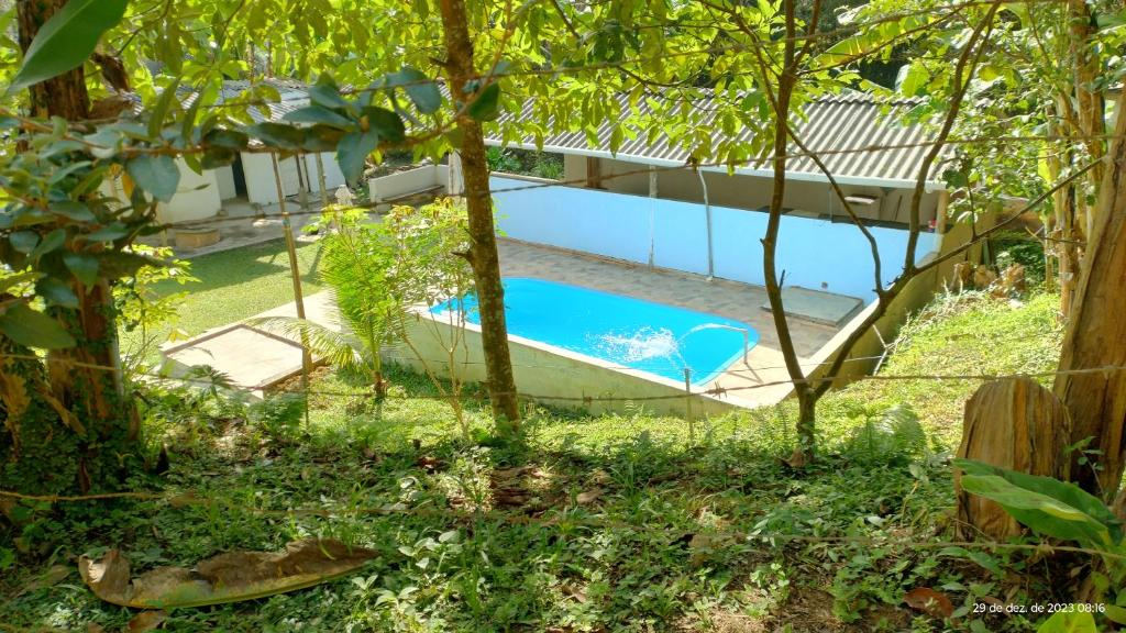 einen Pool inmitten eines Gartens mit Bäumen in der Unterkunft ESPAÇO SHEHERAZADE e PISCINA & LASER in Juquitiba