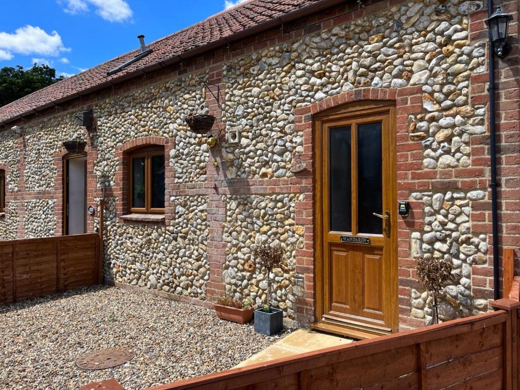 a stone building with a wooden door on it at Mandarin Cottage- quirky upside down retreat - Norfolk in Mileham