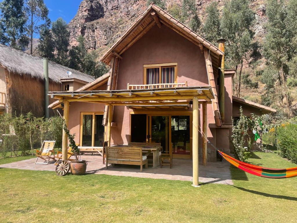 une maison avec une terrasse couverte et un hamac dans la cour dans l'établissement Casa Mayuwasi Cuzco - Valle Sagrado de los Incas, à Calca