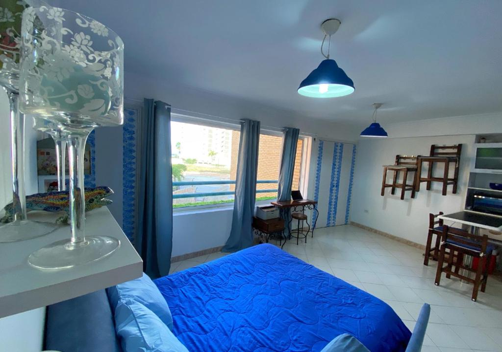 sala de estar con cama azul y ventana en Miramar en Porlamar