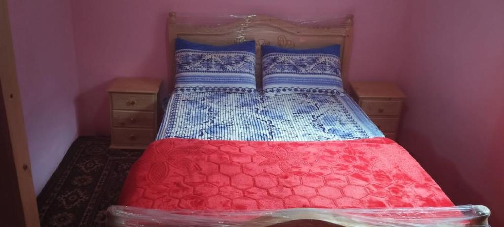 Ce lit se trouve dans un dortoir doté d'une couette rouge et bleue. dans l'établissement Ketama كتامة, à Ketama