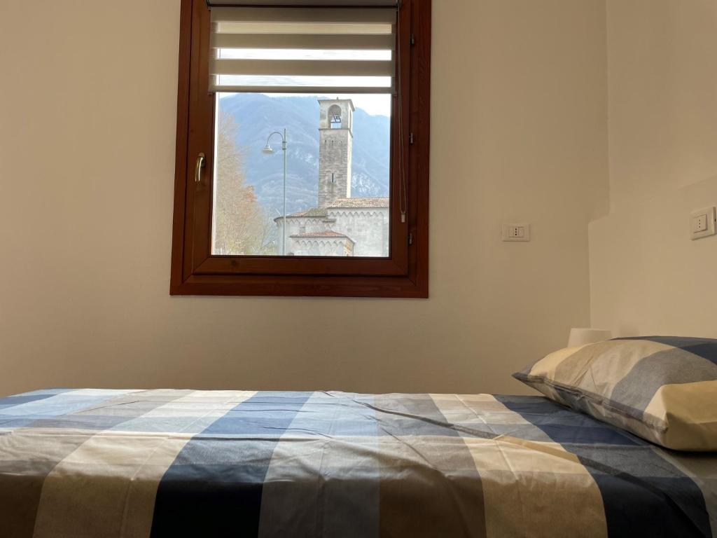 a bedroom with a bed and a window with a clock tower at Twentyone Holiday Home in Pisogne