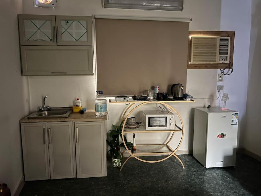 a small kitchen with a microwave and a refrigerator at Family Apartment 1 kilometers Near Masjid Nabawi SAW in Al ‘Awālī