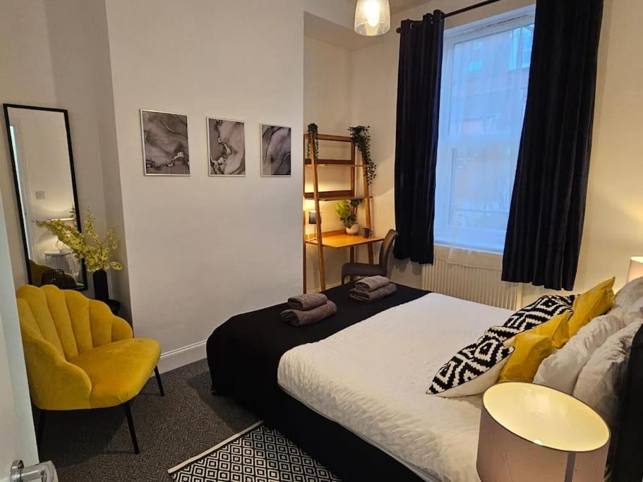 Coolinge Apartment في Kent: غرفة نوم بسرير وكرسي اصفر