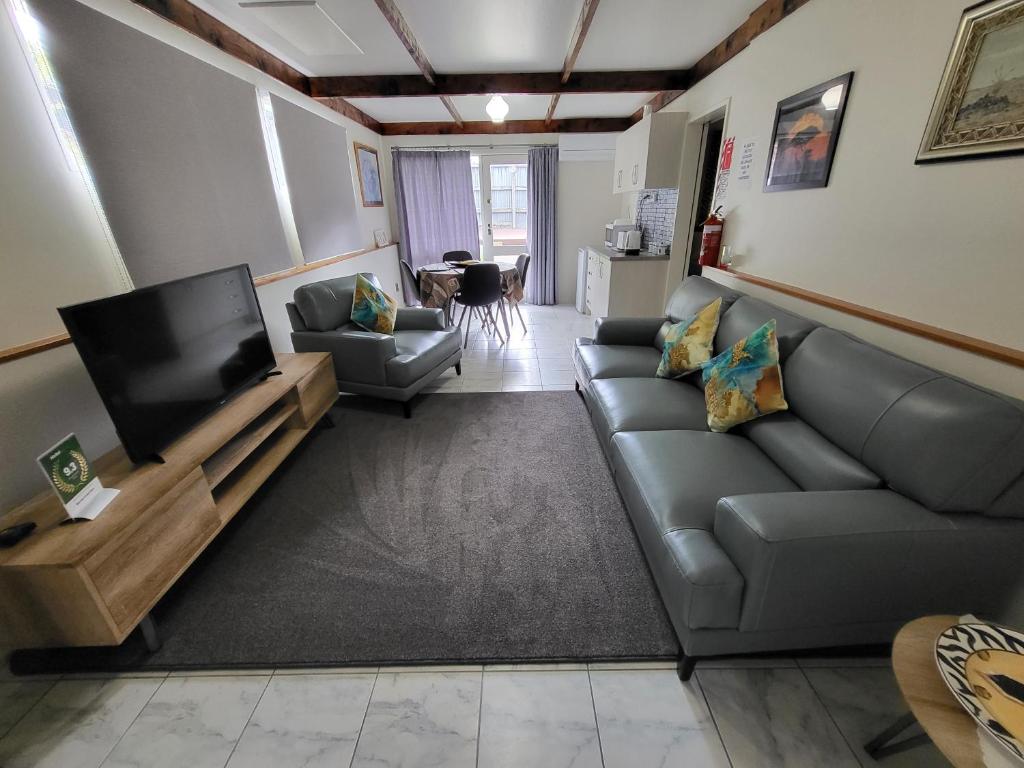 uma sala de estar com um sofá e uma televisão de ecrã plano em BARNES STREET BNB em Timaru
