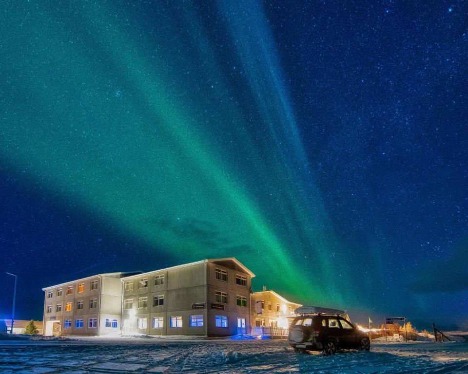 Eine Aurora scheint in den Himmel über einem Gebäude in der Unterkunft Sel - Hótel Mývatn in Mývatn