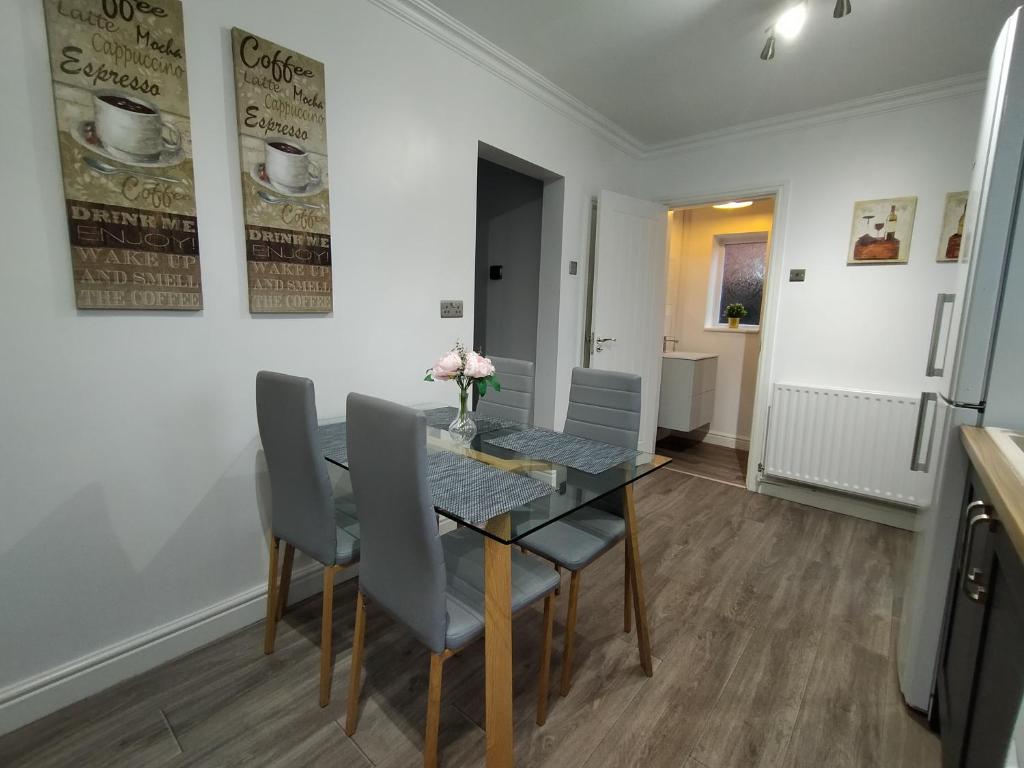uma sala de jantar com uma mesa de vidro e cadeiras em Polaris House - sleeps 6, driveway, garden em Crewe