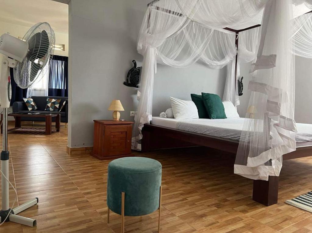 1 dormitorio con cama con dosel y reposapiés verde en Appartement Melissa97- Bât4 Spacieux à Dzamandzar en Nosy Be