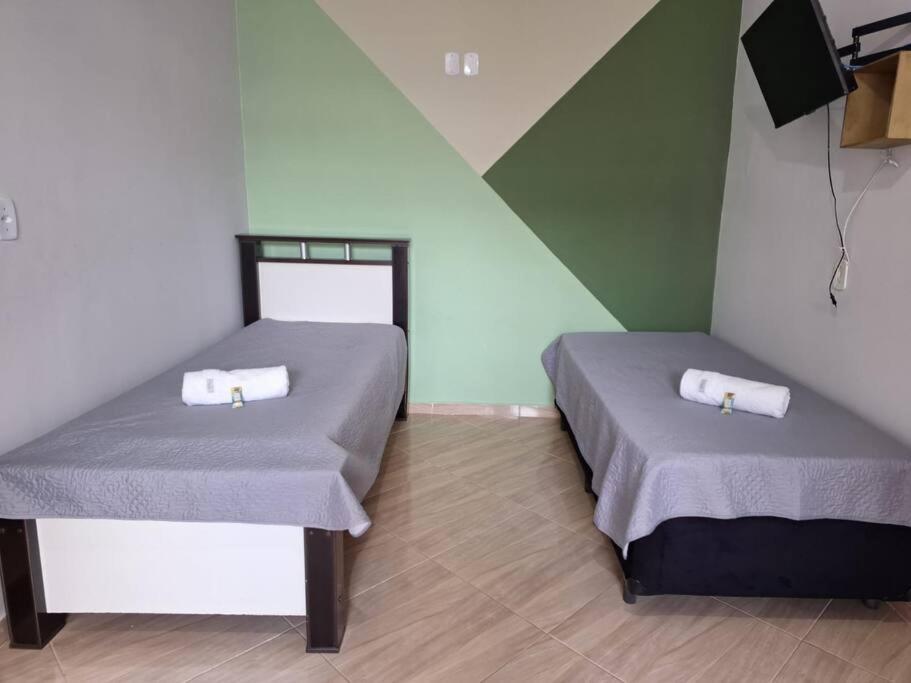 2 Betten in einem Zimmer mit grünen und weißen Wänden in der Unterkunft Edícula c/ wifi e banheiro externo em Capão Bonito in Capão Bonito