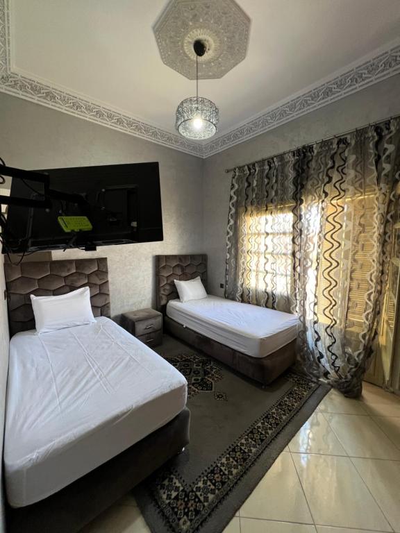 a bedroom with two beds and a flat screen tv at A room in Guéliz only for ladies in Marrakesh