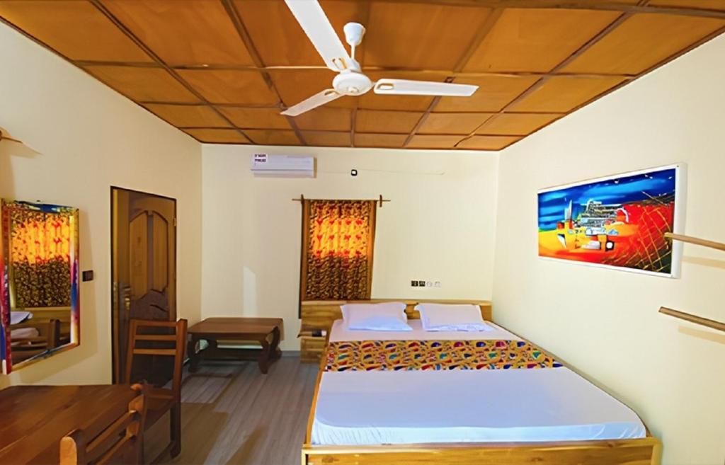 a bedroom with a bed and a ceiling fan at Hotel Eyram in Palimé