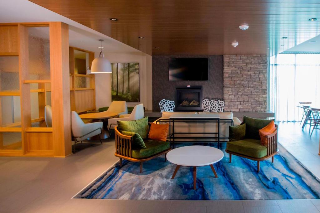 ein Wohnzimmer mit Stühlen, einem Tisch und einem Kamin in der Unterkunft Fairfield Inn & Suites By Marriott Alexandria in Alexandria