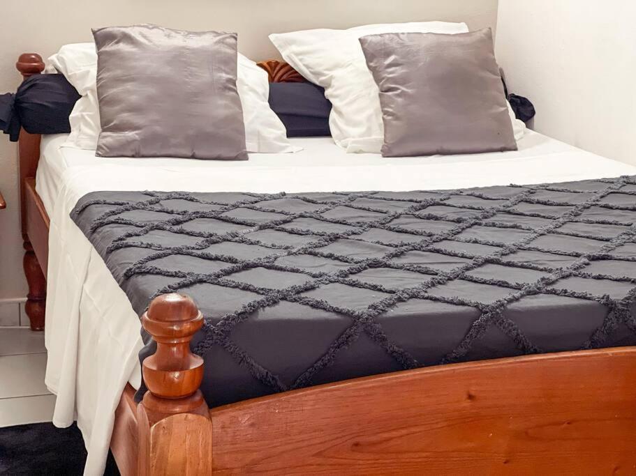 a bed with a black and white comforter and pillows at Studio Jo'kmi in Pointe-Noire