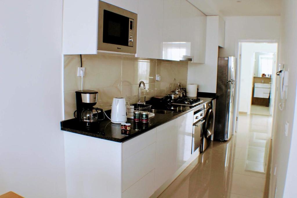 a kitchen with white cabinets and a black counter top at Flamingo Plateau 1A apt on Rua Pedonal Praia Cape Verde in Praia