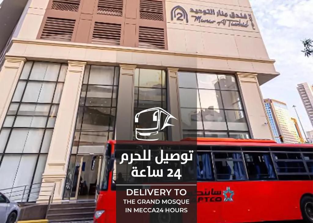 a red bus parked in front of a building at فندق منار التوحيد 2 in Makkah