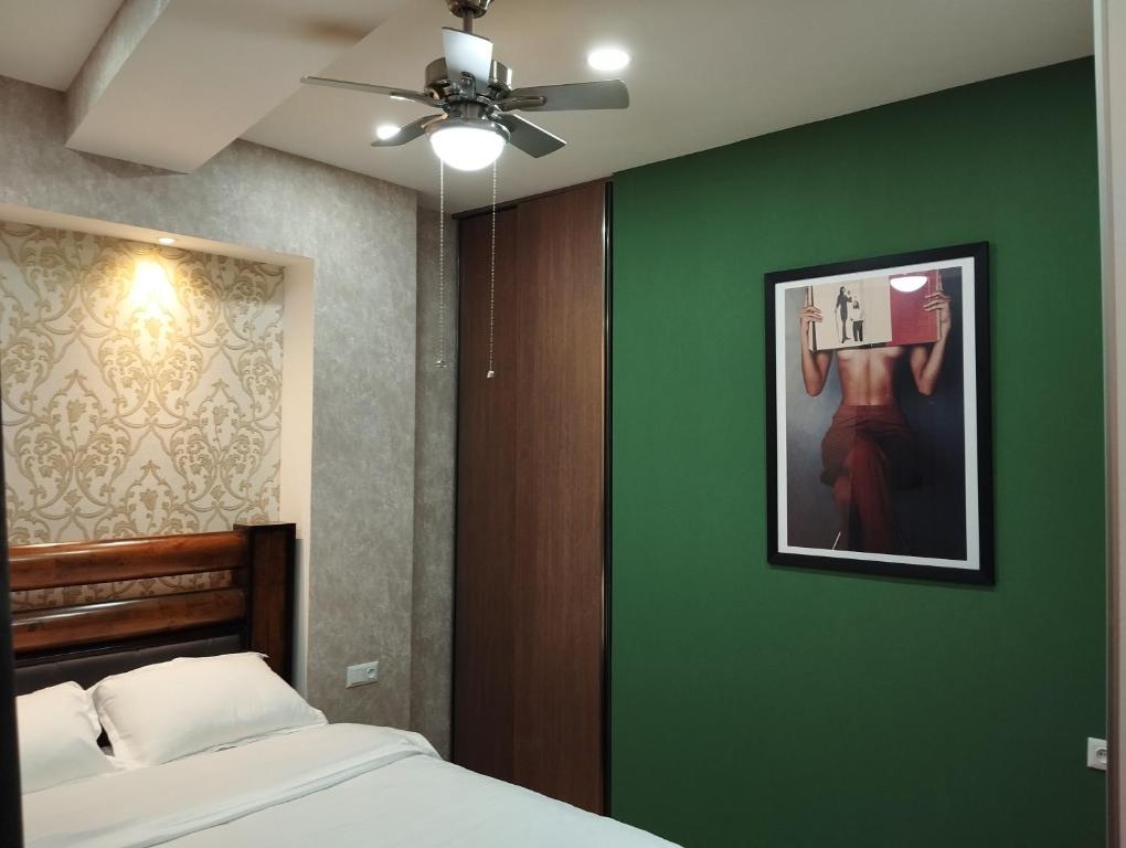 ein Schlafzimmer mit einer grünen Wand mit einem Bett und einem Bild in der Unterkunft House number 1 in kutaisi in Kutaissi