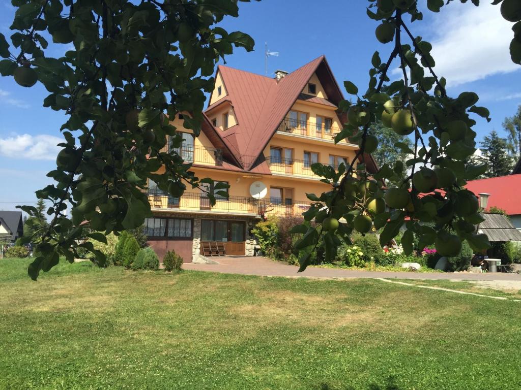 un edificio con un árbol delante de él en Babiarzowie en Białka Tatrzanska