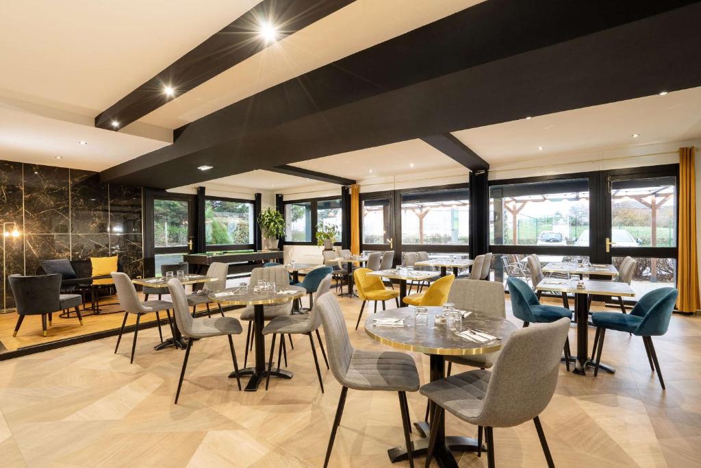un restaurante con mesas, sillas y ventanas en Sure Hotel by Bestwestern Rouvignies Valenciennes en Valenciennes