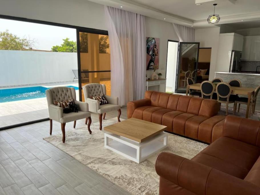 a living room with a couch and chairs and a table at Villa Nohady : luxe, confort, moderne à Saly in Sali Tapé