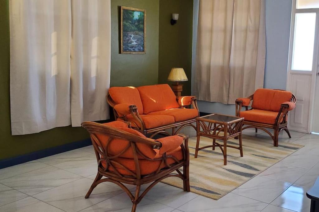 a waiting room with orange chairs and a table at 28 Steber in Roseau