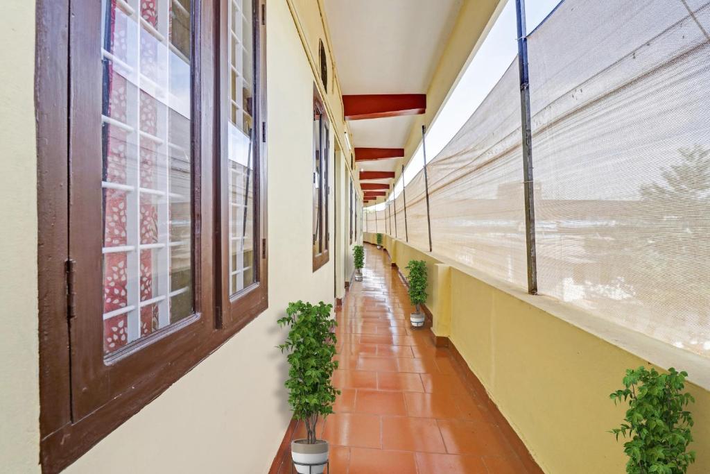 un pasillo vacío con ventanas y macetas en OYO Hotel Faizalia Tourist Home, en Perumpāvūr