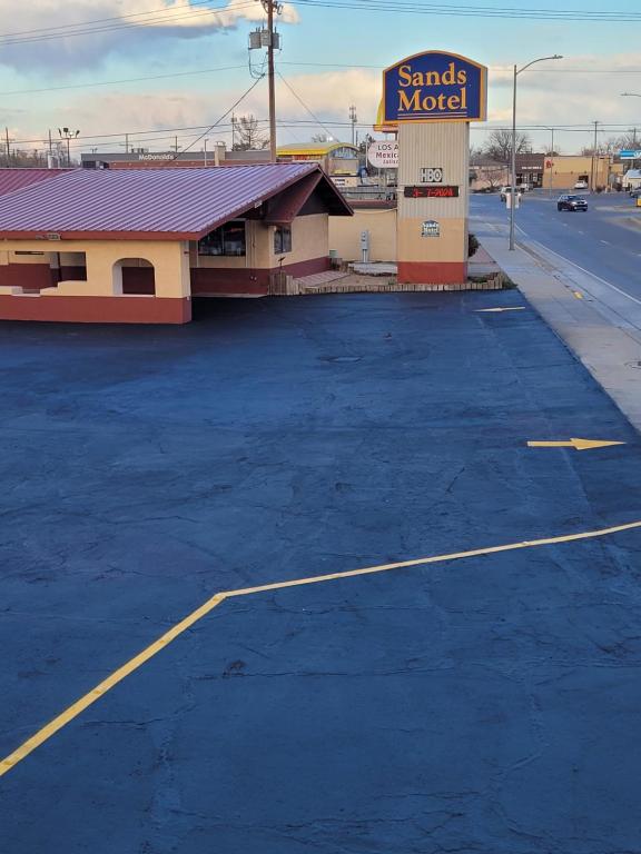 un parcheggio vuoto di fronte a un motel di sabbia di Sands Motel a Portales