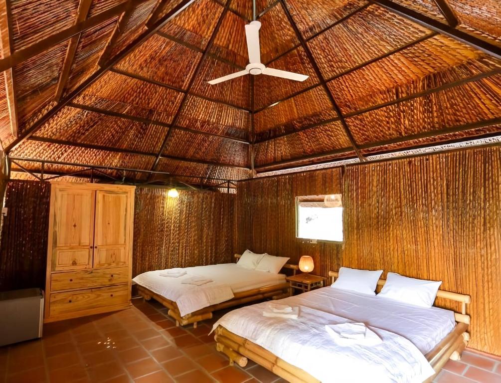 a bedroom with two beds in a straw roof at Dan Sinh Homestay in Can Tho
