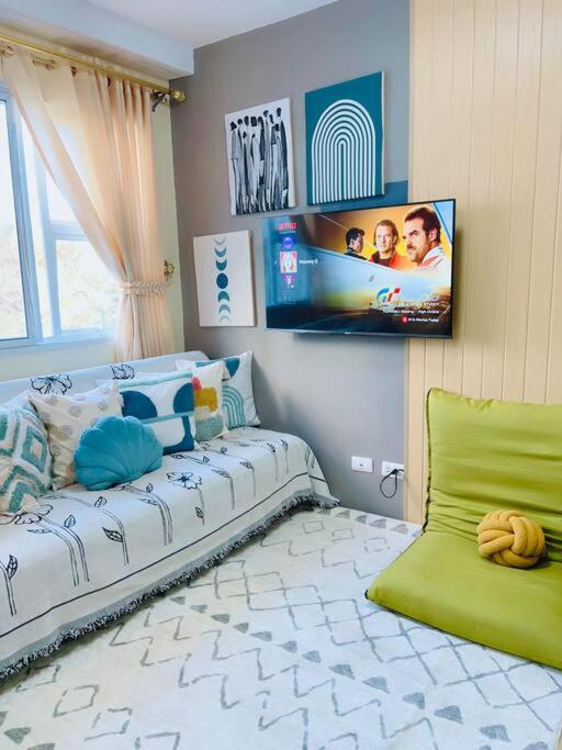 ein Wohnzimmer mit einem Sofa und einem TV an der Wand in der Unterkunft Pineview Haven in Baguio in Baguio City