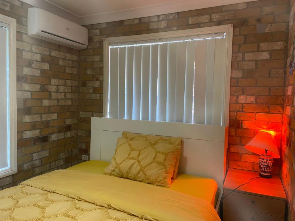 1 dormitorio con 1 cama con ventana y lámpara en Spacious studio unit, en Rochedale South