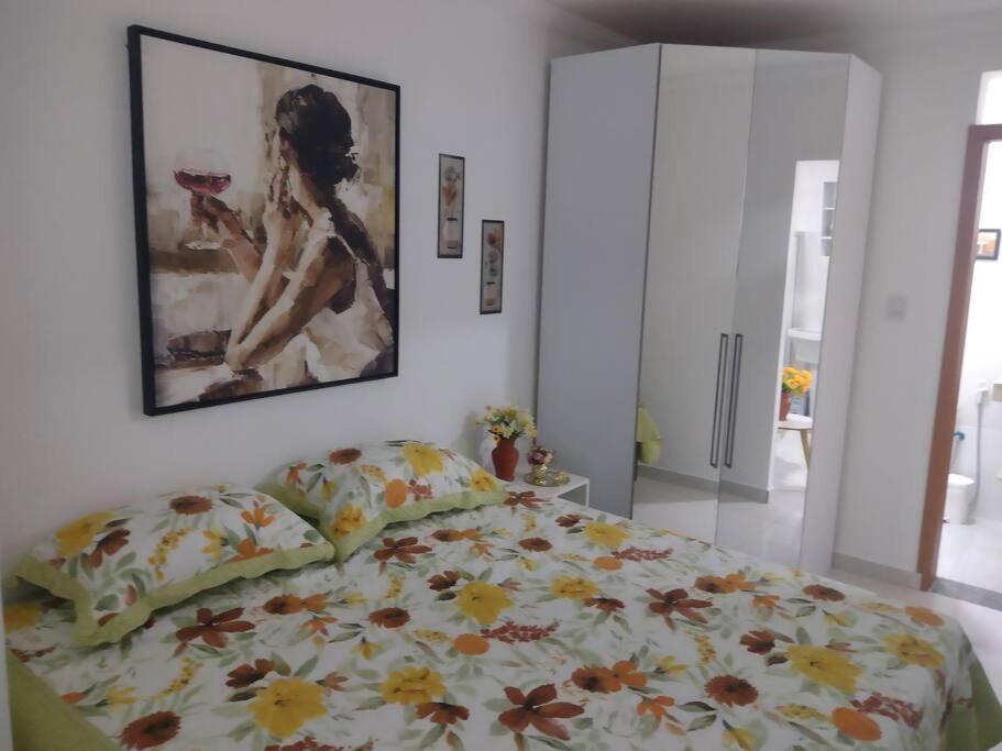 een slaapkamer met een bed en een schilderij aan de muur bij Flat Espetacular Recanto de Minas in São Lourenço
