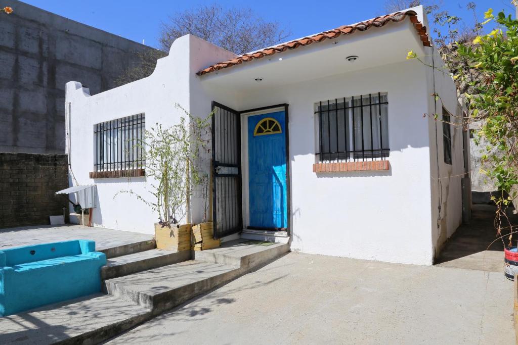 a white house with a blue door at Casa completa a 5 minutos de la playa en Crucecita Huatulco in Santa Cruz Huatulco