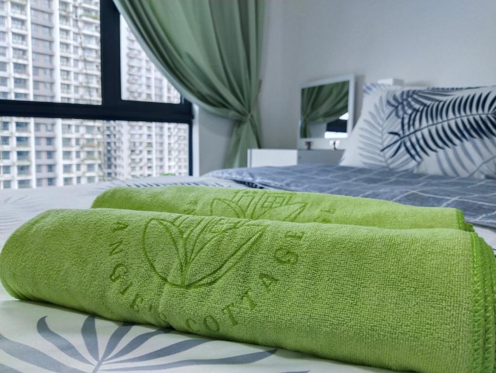 two green towels on a bed in a bedroom at Holiday SweetHome at Forest City 2BR1B with TV Box 4-6pax 1807 in Gelang Patah