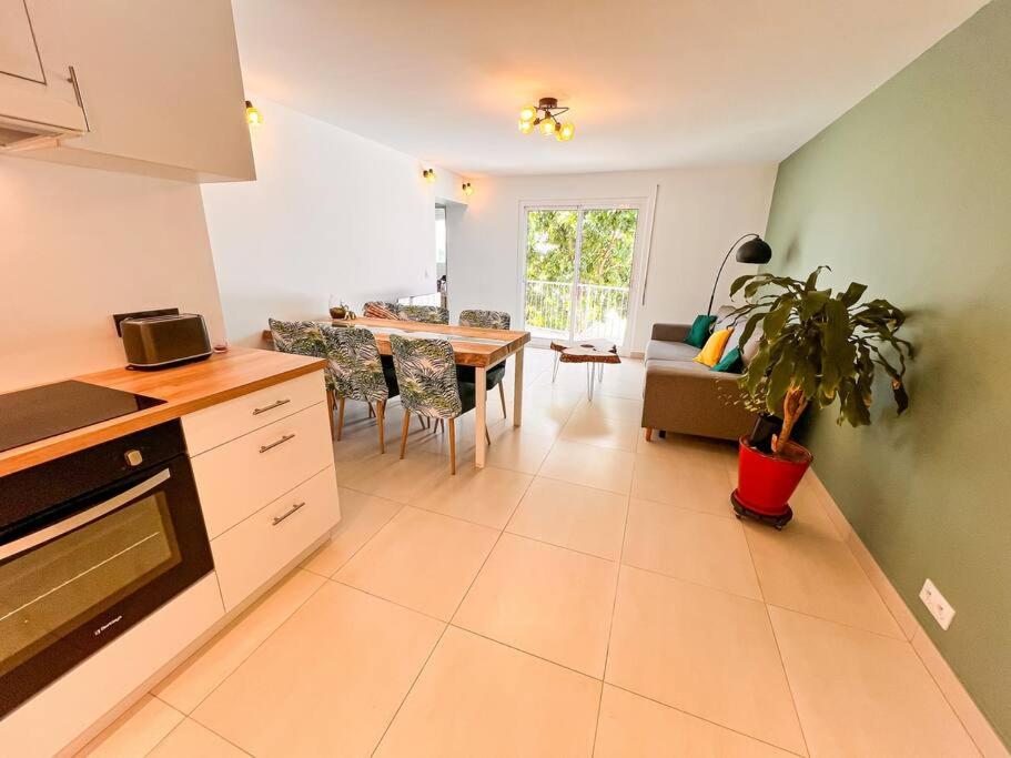 een keuken en een woonkamer met een tafel en een plant bij La Perle Azurée in Noumea