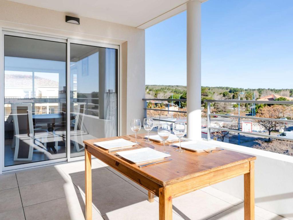 - une table en bois avec des verres à vin sur le balcon dans l'établissement Appartement T3 Climatisé avec WIFI, Balcon et Parking à 300m de la Plage - Narbonne Plage - FR-1-409-255, à Narbonne