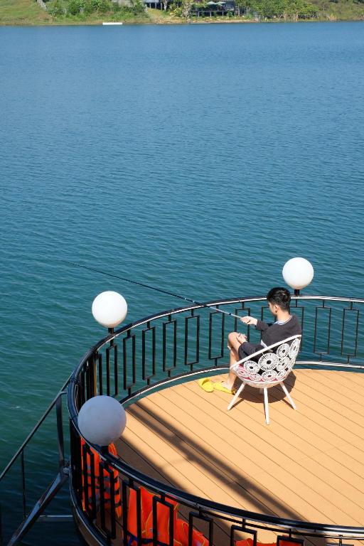 a man sitting in a chair on a deck on a boat at Hồ Mây Homestay in Bảo Lâm