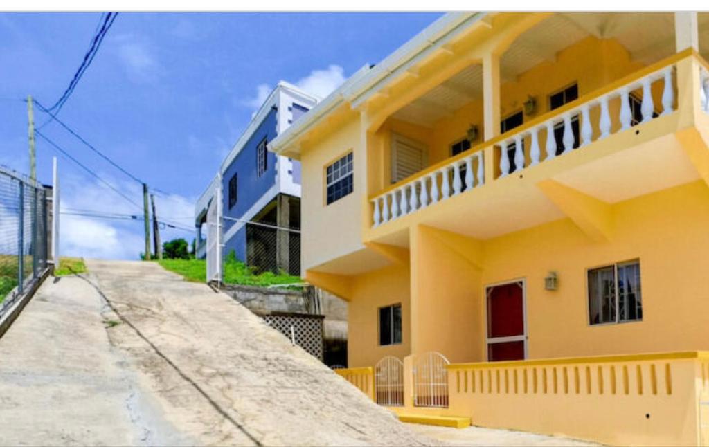 a yellow house with a balcony on a street at Patrickville in Calliste Land Settlement