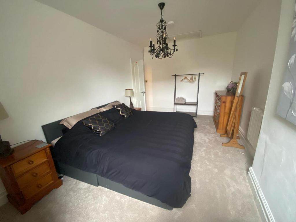 Un dormitorio con una gran cama negra y una lámpara de araña. en North Street Flat, en Bristol