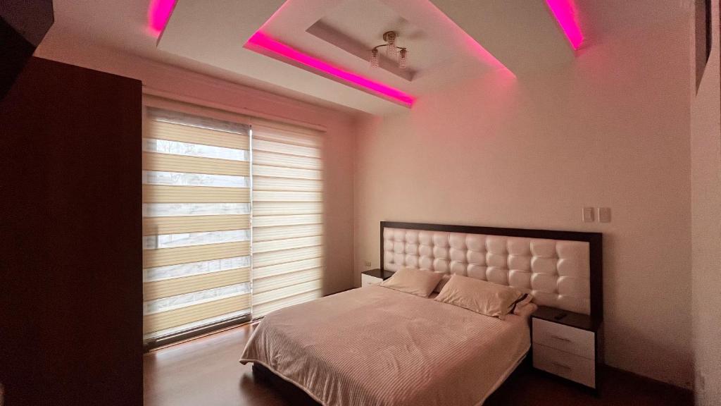 ein Schlafzimmer mit einem Bett mit rosa Lichtern an der Decke in der Unterkunft Departamento moderno con gran espacio in Cuenca