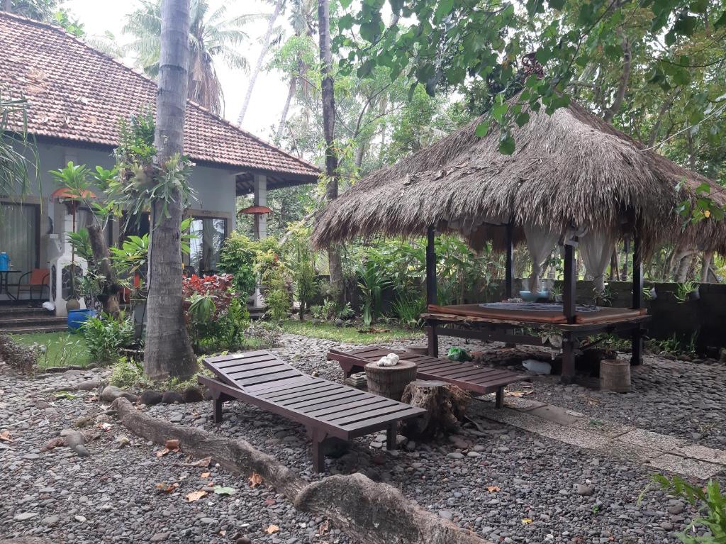 a picnic table and a hut with a table and benches at Homestay on the beach in Tejakula