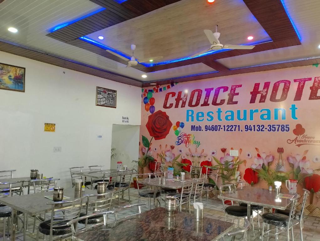 a restaurant with tables and chairs and a sign on the wall at CHOICE HOTEL AND RESTAURANT in Hanumāngarh