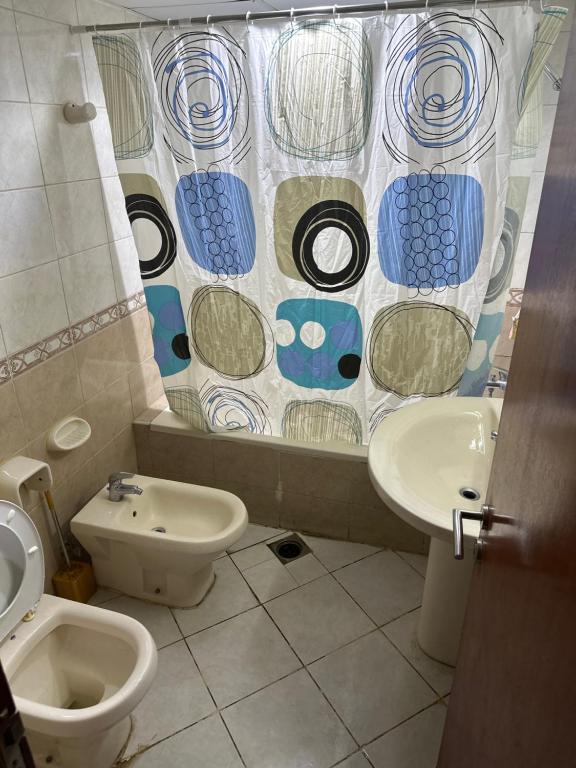 a bathroom with a toilet and a sink and a shower curtain at El Mahatta Building in Sharjah