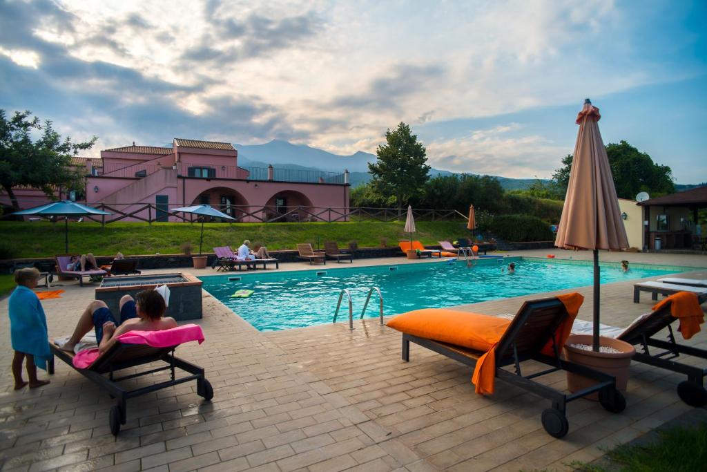 a swimming pool with people sitting on chairs next to it at Agriturismo Tenuta San Michele in Santa Venerina