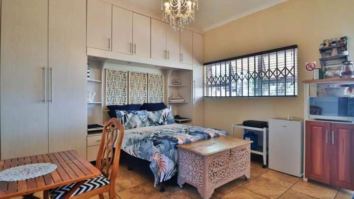 1 dormitorio con cama, mesa y cocina en 54 Asteria Ave, Larnaco Estate en Kingsborough
