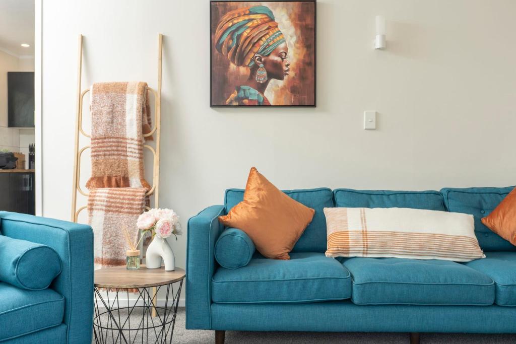 un sofá azul en una sala de estar con una pintura en la pared en Riverside Retreat en Whangarei