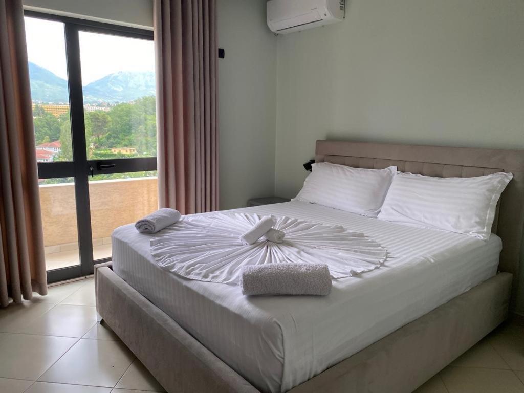 ein Schlafzimmer mit einem großen Bett und einem großen Fenster in der Unterkunft Hotel Agron in Tirana