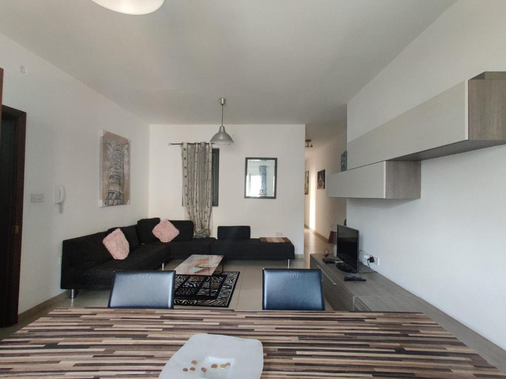 a living room with a black couch and two chairs at St Julians Sliema 3 minutes walk from promenade 3 bedroom apartment in Sliema